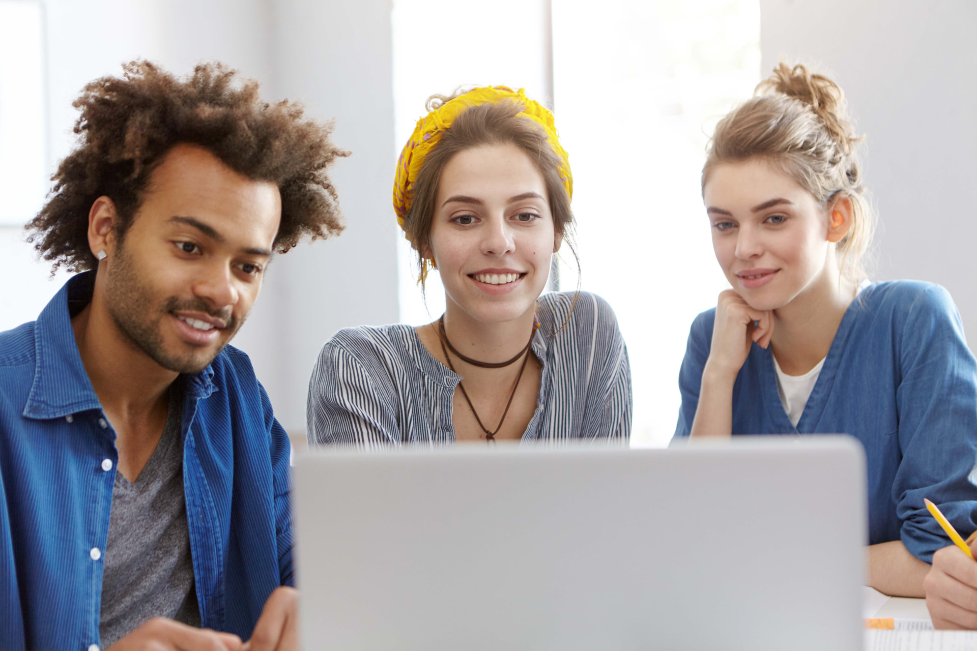 Diverse group of young professionals collaborating around a laptop